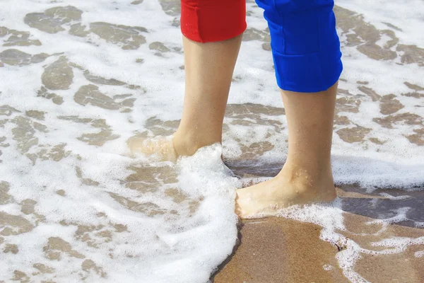 Hermosas piernas de mujer con pantalones metidos caminando en una playa — Foto de Stock