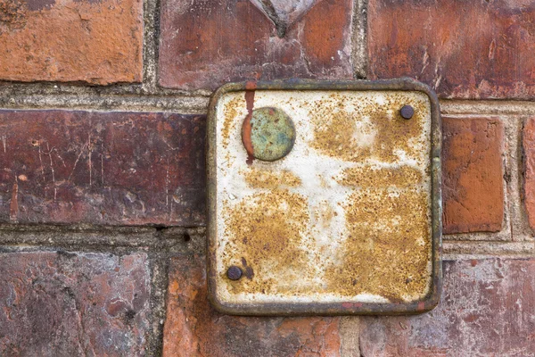 Placa enferrujada vermelha metálica velha em uma parede de tijolo — Fotografia de Stock