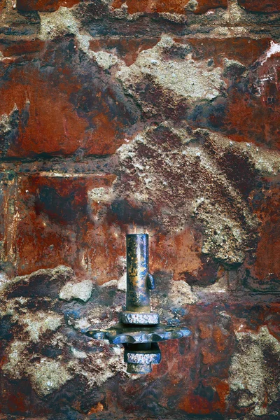 Velho detalhe enferrujado vermelho metálico em uma parede de tijolo — Fotografia de Stock