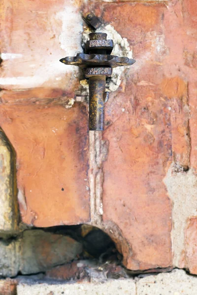 Viejo detalle oxidado rojo metálico en una pared de ladrillo — Foto de Stock