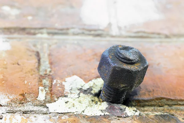 Vieux boulon rouillé dans un mur de briques rouges — Photo