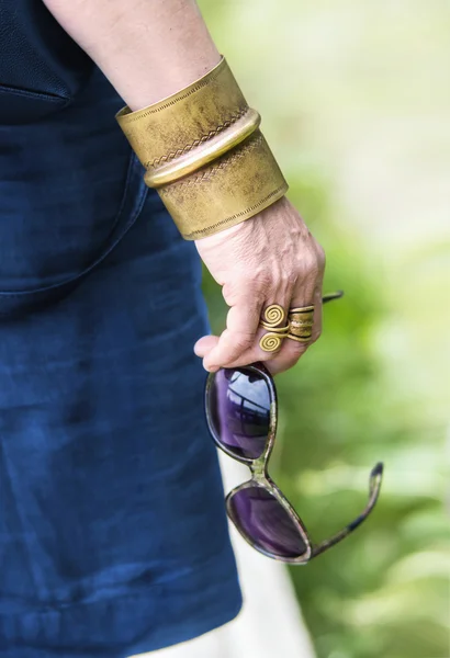 Kvinnans hand med glasögon och mässing smycken — Stockfoto