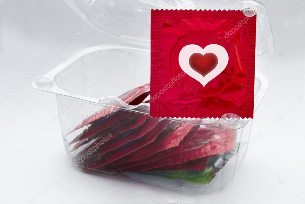 Red condom with heart and a transparent box with a lot of condom