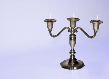 Silver candlestick holding three almost burnt-out candles clipart