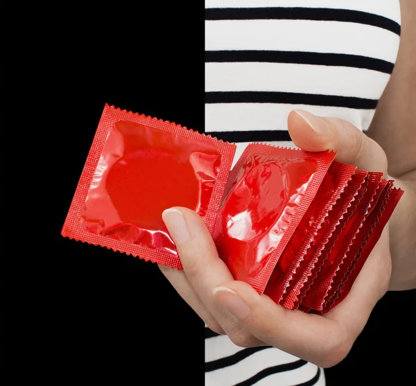 Girl with a striped shirt holding many red condoms. — Stock Photo, Image