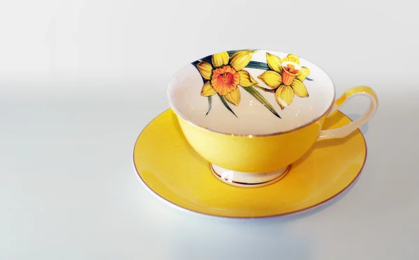 Taza amarilla con flores de narciso para un té — Foto de Stock