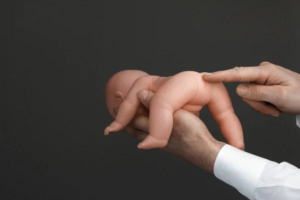Le mani degli uomini con una bambola bambino — Foto Stock