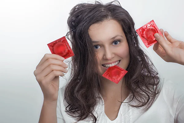 Fille avec trois paquets de préservatifs rouges — Photo