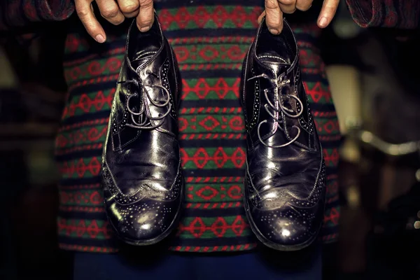 Oude zwarte mannen schoenen in handen van mannen — Stockfoto