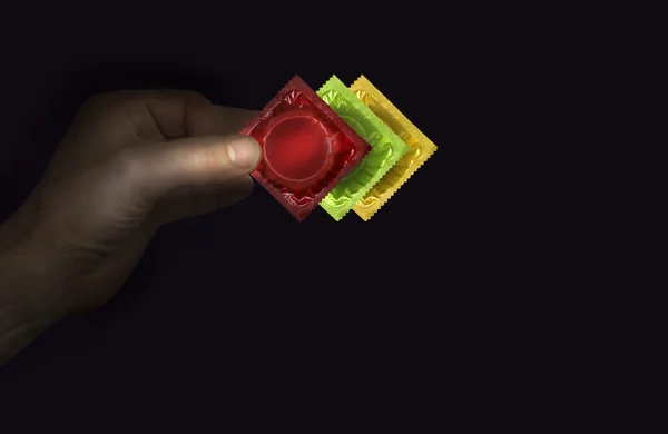 Man's hand with a red condom packs — Stock Photo, Image