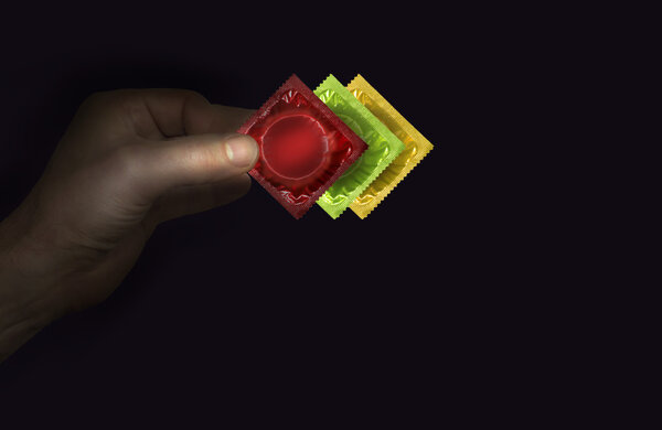 Man's hand with a red condom packs