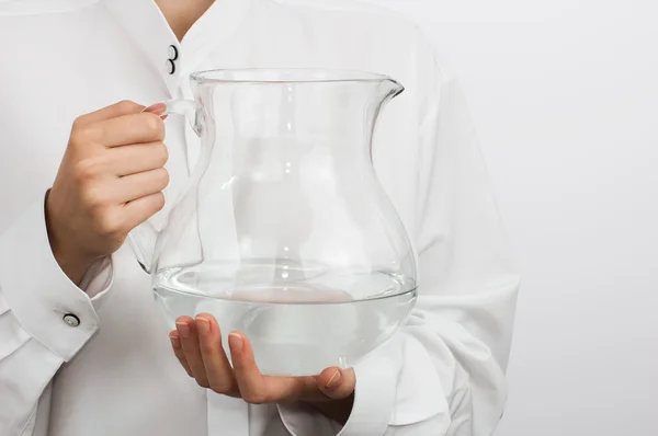 Girl's hands with a glass pitcher — Stock Photo, Image