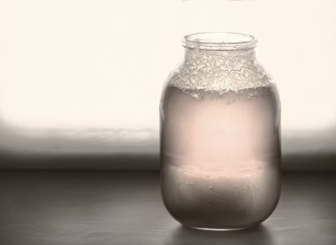 Büyük kavanoz yarım kristalize tatlım bir pencere üzerinde