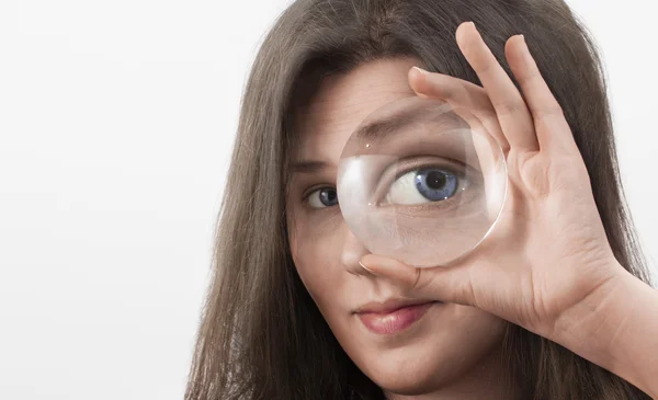 Vrouwelijke blauw oog kijken door vergrootglas — Stockfoto