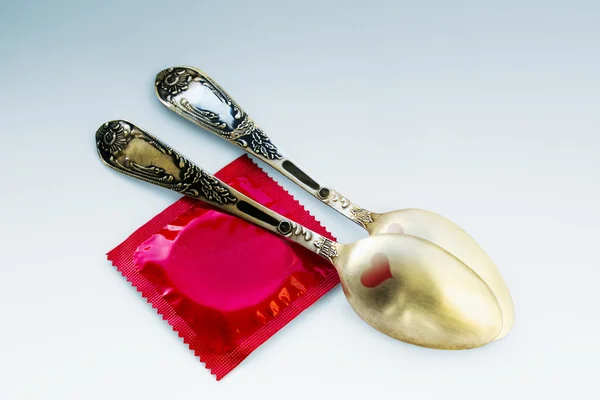 Dwa złote łyżeczki z czerwone serca i prezerwatywa czerwony — Zdjęcie stockowe