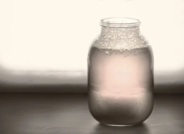 Big jar of half crystallized honey on a windowsill — Stock Photo, Image