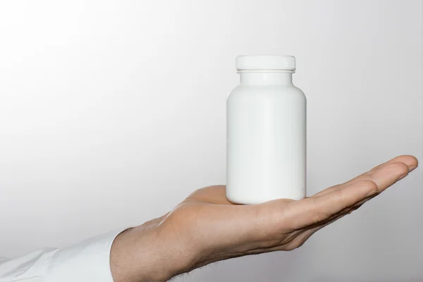 Männerhand mit weißer Flasche — Stockfoto