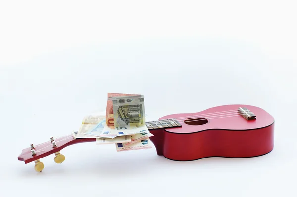 Ukelele de guitarra pequeña y billetes en euros — Foto de Stock