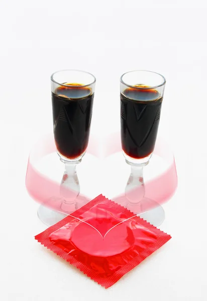 Czerwony prezerwatywy i dwie szklanki z ciemny napój — Zdjęcie stockowe
