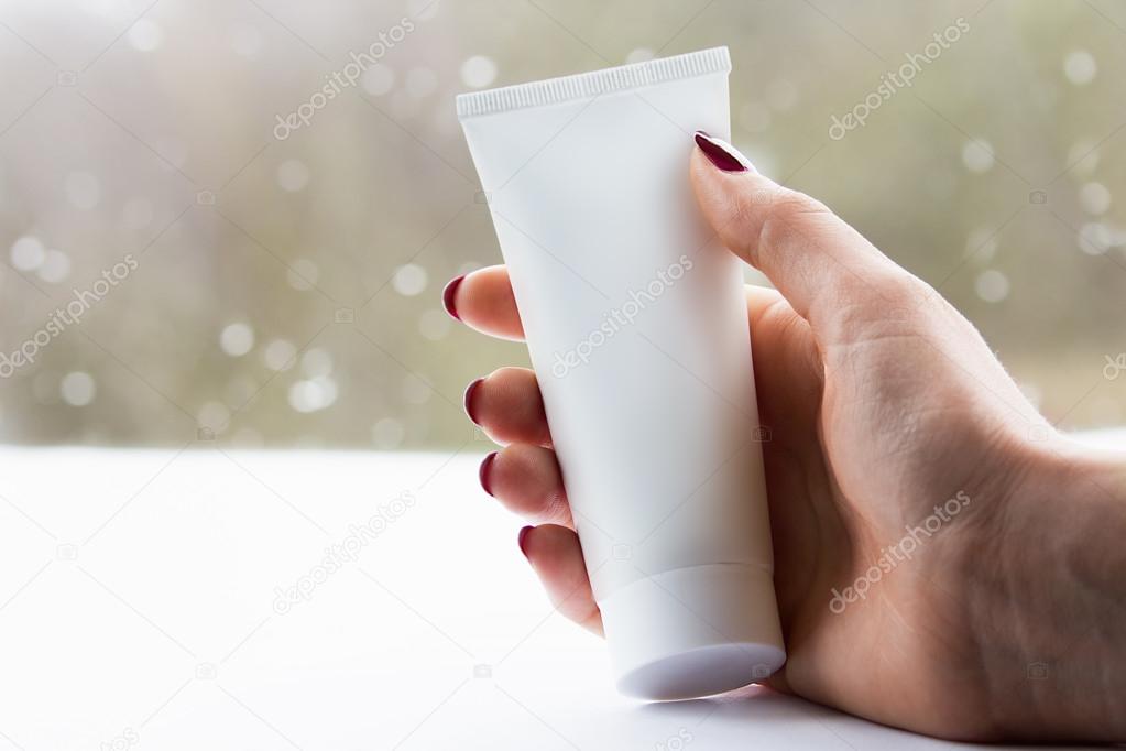 Woman hand with a white cream tube