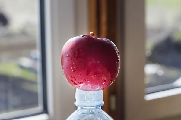Red apple on a bottle with mineral water — Stock Photo, Image