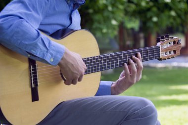 Young male playing a classic guitar outside