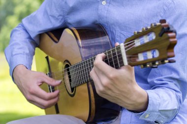 Young male playing a classic guitar outside