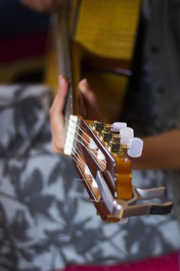 Acoustic guitar's fretboard head and girl's hand on a fretboard