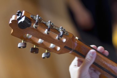 Akustik gitar klavyesine ve genç erkeğin el