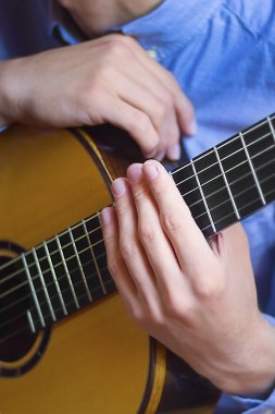 Akustik gitar klavyesine ve genç erkeğin eller