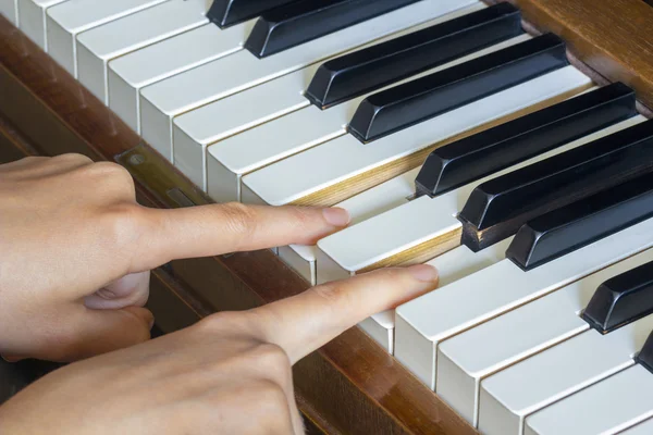 Flickorna händer två fingrar hålla nertryckta tangenter hos ett piano — Stockfoto