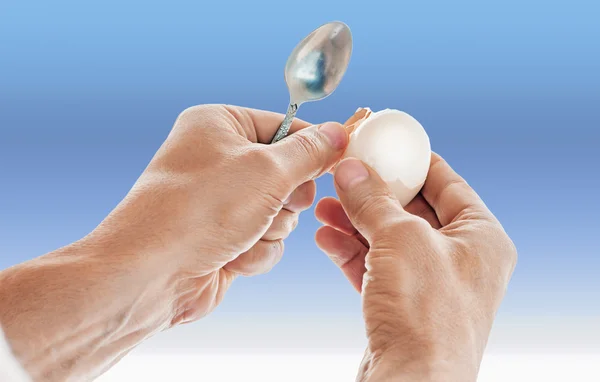 Mans hands holding peeled egg anf teaspoon — стоковое фото