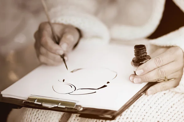 Mãos femininas desenhando uma caricatura com tinta preta — Fotografia de Stock