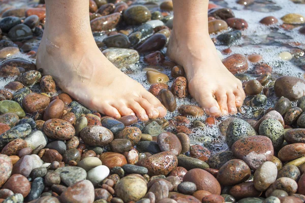 Ženské nohy na pláži kameny — Stock fotografie