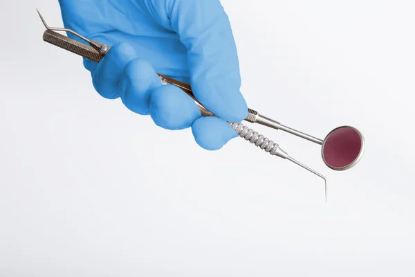 Mano con un guante médico azul sosteniendo herramientas odontológicas — Foto de Stock