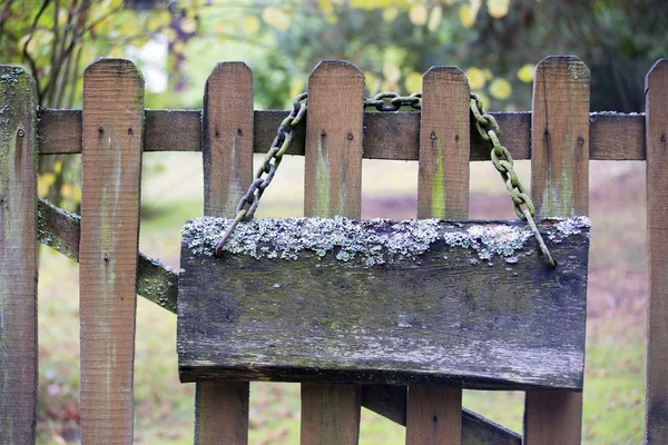 Antiguo letrero musgoso con cadena en una cerca de madera — Foto de Stock