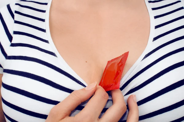 Mujer sosteniendo un condón rojo en su escote —  Fotos de Stock