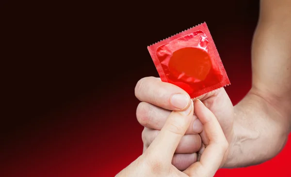 Man Hand Giving Woman Hand Red Condom Red Gradient Background — Stock Photo, Image