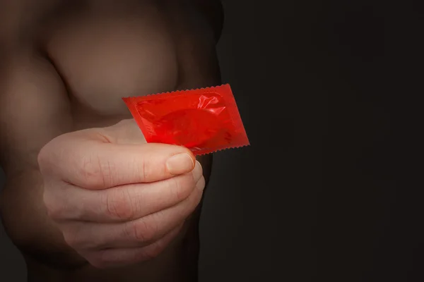 Man Hand Giving Red Condom Dark Gradient Background — Stock Photo, Image