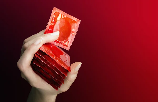 Woman's hand with seven  red  condoms — Stock Photo, Image