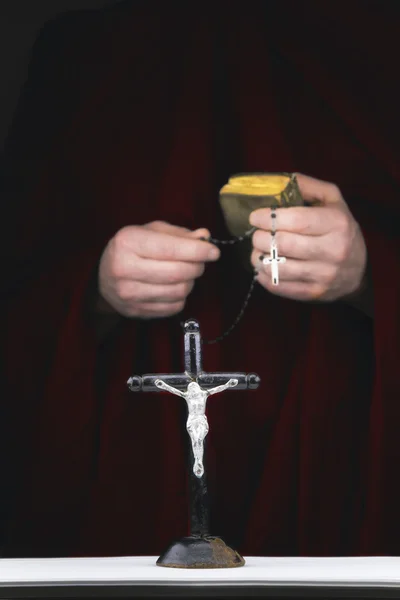 Manos de monje misterioso con capa, biblia, rosario negro y cr — Foto de Stock