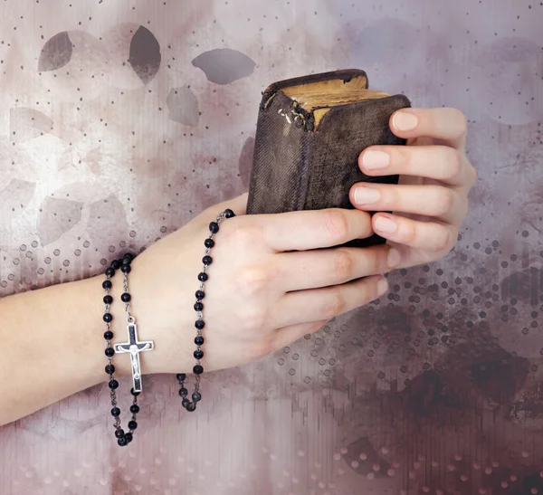 Las manos de una joven con un rosario y una Biblia — Foto de Stock