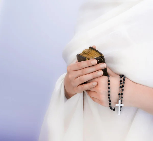 Handen van de jonge vrouw met een rozenkrans en een Bijbel — Stockfoto