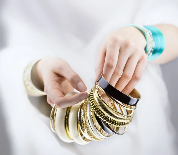 Руки девушки с золотыми браслетами — стоковое фото
