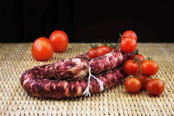 Salchicha ahumada con un manojo de tomates rojos pequeños — Foto de Stock