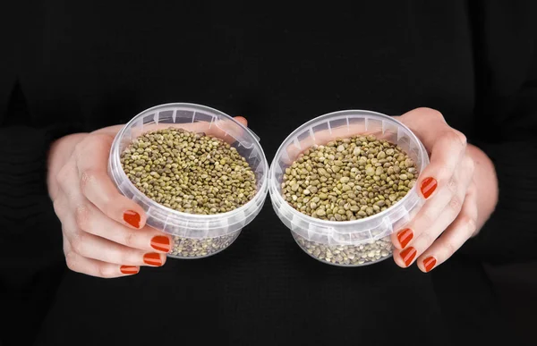 Two plastic jars with hemps in woman's hands — Stock Photo, Image