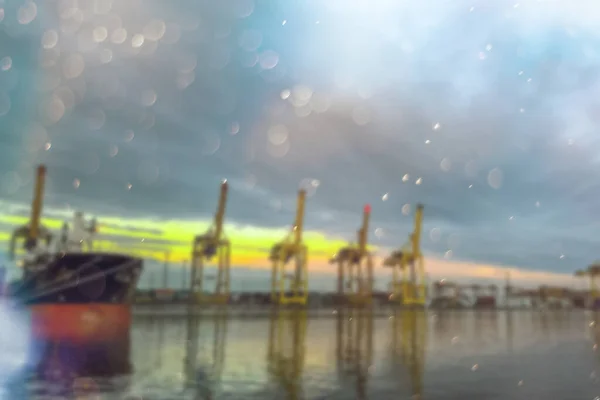 blurred image is a cargo cranes in the port. Sea cargo transportation, abstract background.
