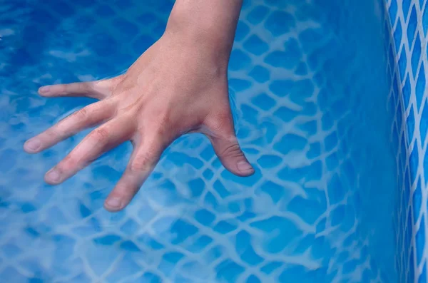 children's hands in the water in the pool