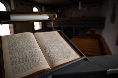 Old Vintage German Bible on Pulpit in European Medieval Church Close up Blurred Background and Copy Space clipart