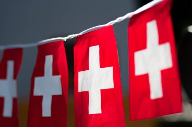 String banner of small swiss Switzerland Red and White Cross flags hanging up with a close-up perspective with blurred background and copy space. clipart